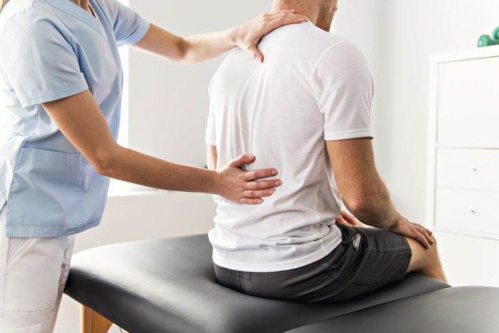 man sitting on table at physical therapy or chiropractor
